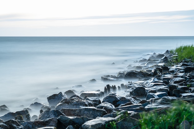 Faszinierende Ansicht des ruhigen Meeres mit Steinen an der Küste unter dem klaren Himmel