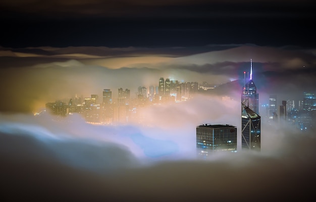 Faszinierende Aufnahme der Wolkenkratzer einer Stadt, die nachts mit Nebel bedeckt ist