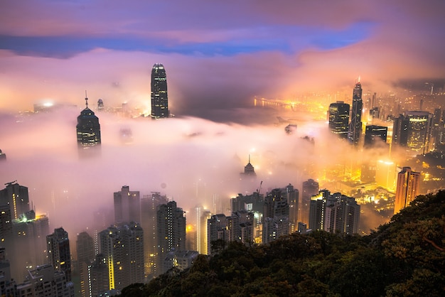 Faszinierende Aufnahme der Wolkenkratzer einer Stadt, die nachts mit Nebel bedeckt ist