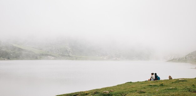 Faszinierende Aussicht auf den nebligen See mit sitzenden Menschen people