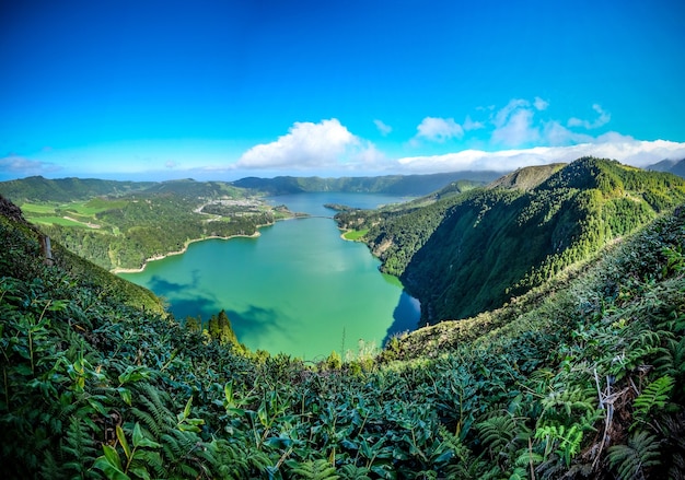 Faszinierende Aussicht auf den See, umgeben von Bergen, die unter dem blauen Himmel grün bedeckt sind