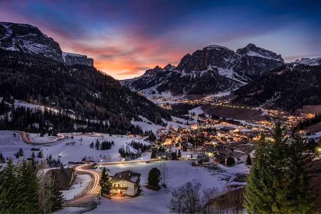 Faszinierende Aussicht auf die Häuser auf den schneebedeckten Feldern, umgeben von Bergen und Bäumen