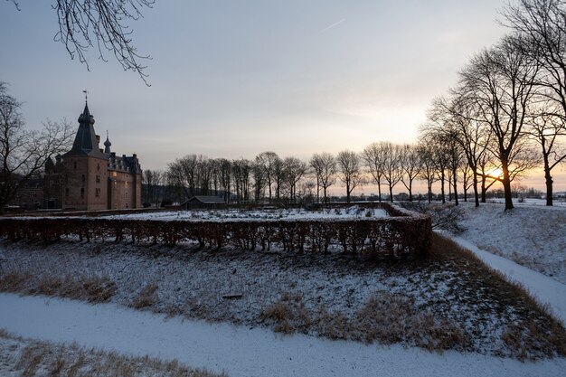 Faszinierender Sonnenaufgang über dem historischen Doorwerth Schloss während des Winters in Holland