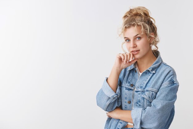 Fasziniert gutaussehende skandinavische blonde lockige Frau blaue Augen schauende Kamera interessiert zuhören guter Rat Vorschlag stehend nachdenklich weißer Hintergrund erwägen, Entscheidung zu treffen