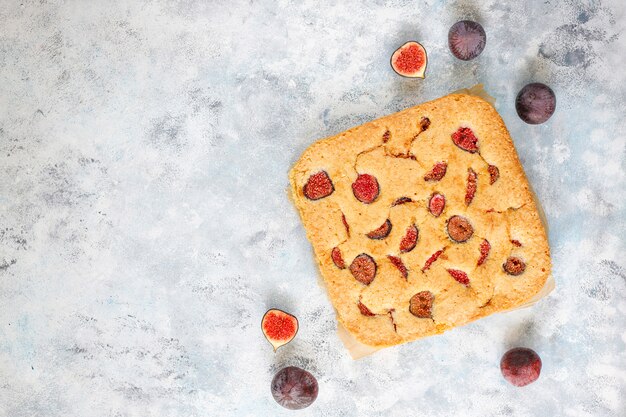 Feigenkuchen mit frischen Feigen auf grauem Betonhintergrund.