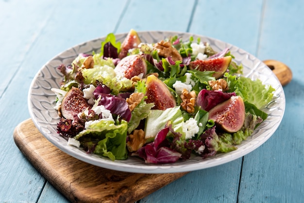 Kostenloses Foto feigensalat mit käse und walnüssen auf blauem holztisch