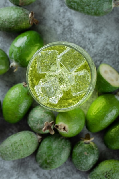 Kostenloses Foto feijoa-früchte und ein glas saft auf marmoroberfläche.