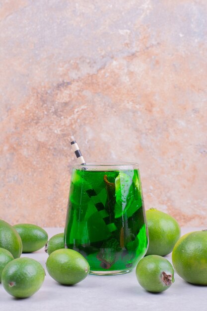 Feijoa und Mandarinen mit einem Glas grünem Saft.