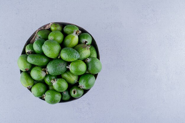 Feijoas stapelte sich in einer Metallvase auf Marmorhintergrund. Foto in hoher Qualität