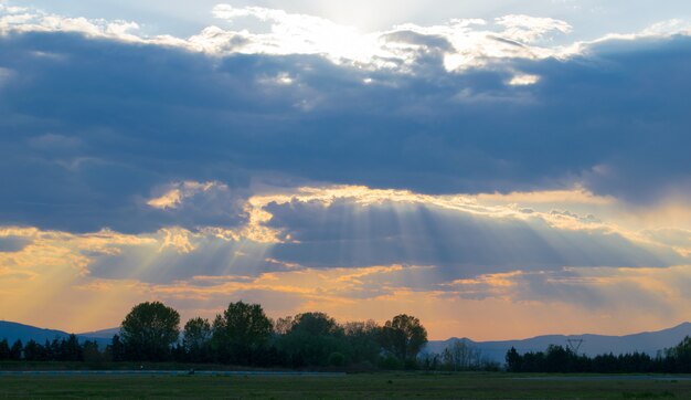 Feld bedeckt im Grünen unter einem bewölkten Himmel während eines schönen Sonnenuntergangs am Abend