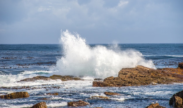 Felsen, umgeben vom welligen Meer unter dem Sonnenlicht und einem bewölkten Himmel tagsüber in Südafrika