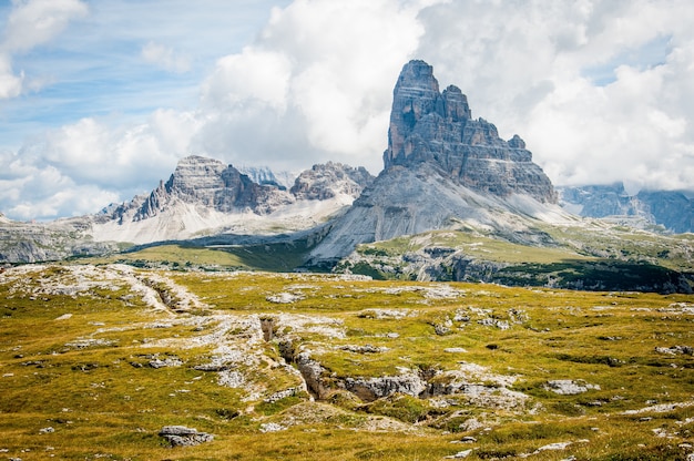 Felsformation auf weitem Feldgras unter bewölktem blauem Himmel während des Tages