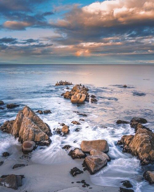 Felsformationen im Meer unter den weißen Wolken