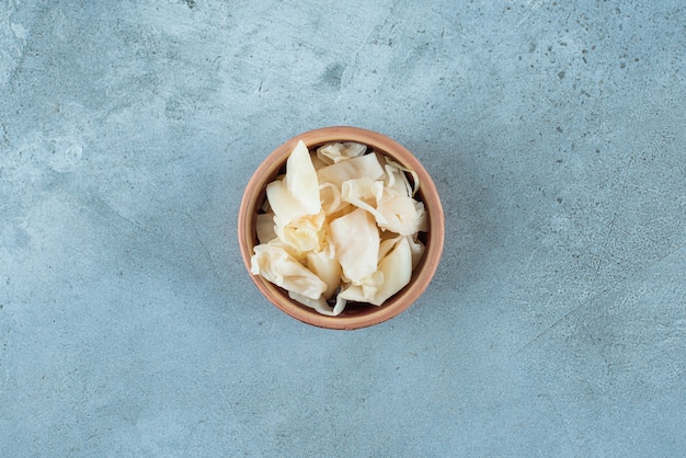 Fermentiertes Sauerkraut mit Karotten in einer Schüssel auf dem blauen Tisch.