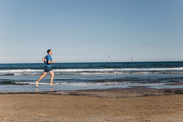 Kostenloses Foto fernansicht des mannes, der am strand läuft