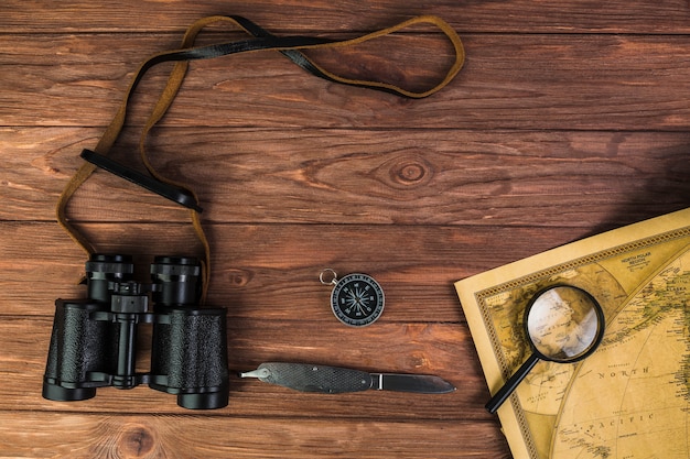 Fernglas, Kompass und Messer mit Mikroskop auf Vintage Karte