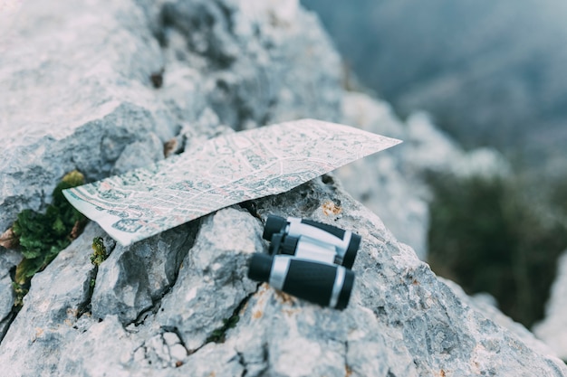 Fernglas und Karte auf Felsen