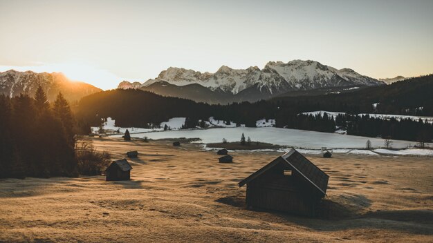 Fernschuss eines Tals mit einem Hüttenhaus und hohen schneebedeckten Bergen