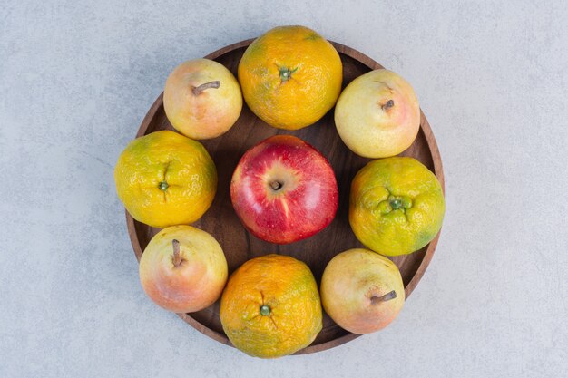 Fersh Bio-Früchte auf Holzbrett. Mandarine, roter Apfel und Birne.