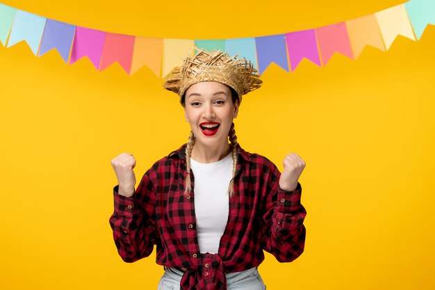 Festa junina blondes süßes mädchen im brasilianischen festival des strohhutes mit den bunten fahnen, die fäuste halten