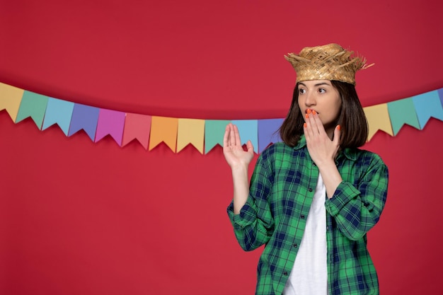 Festa junina fröhliches süßes mädchen mit strohhut, das das brasilianische festival feiert, das den mund bedeckt