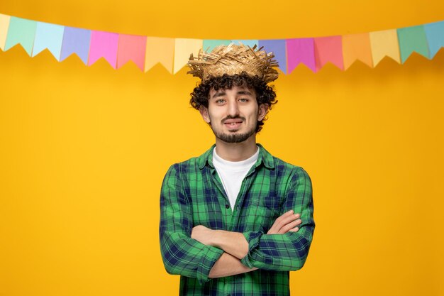 Festa junina junger süßer kerl mit strohhut und bunten flaggen brasilianisches festival kreuzte die hände