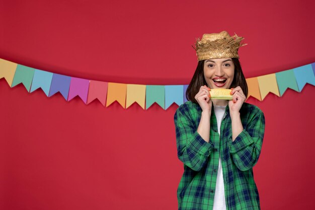 Festa junina mit strohhut junges mädchen feiert brasilianisches festival, das gelben mais isst