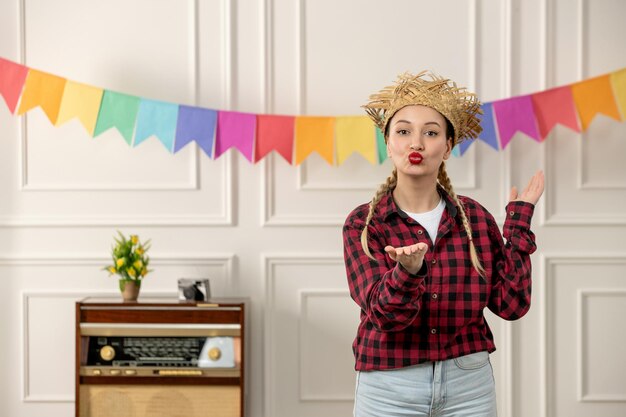 Festa junina süßes mädchen im brasilianischen hochsommer mit strohhut und retro-radio-bunter flagge, die kuss sendet