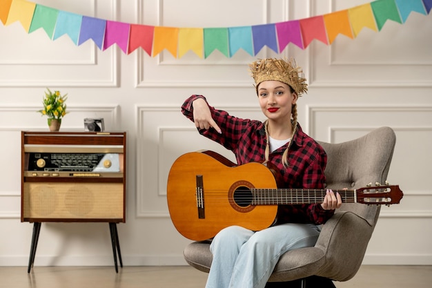 Festa junina süßes mädchen im brasilianischen hochsommer mit strohhut und retro-radio, das auf gitarre zeigt