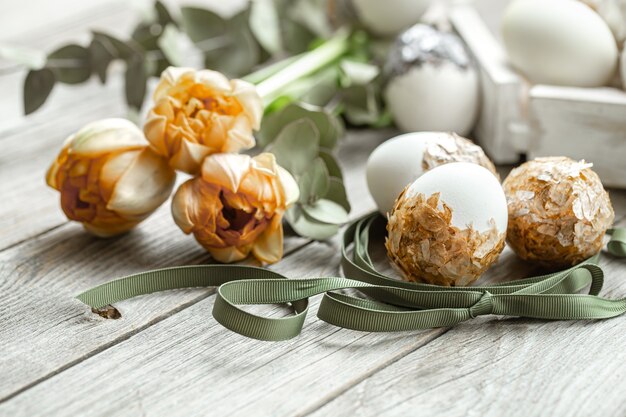 Festliche Komposition für die Osterferien mit dekorativen Eiern und frischen Blumen.