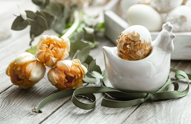 Festliche Komposition für die Osterferien mit dekorativen Eiern und frischen Blumen.