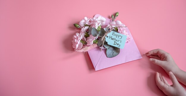 Festliche Komposition mit einem Umschlag mit frischen Blumen und der Aufschrift Happy Mother's Day Flat Lay.