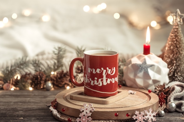 Festliche Komposition mit einer roten Tasse mit der Aufschrift Frohe Weihnachten.