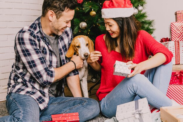 Festliche Paare, die Weihnachten mit Hund feiern