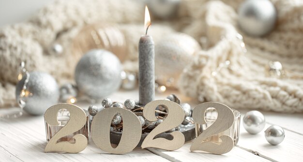 Festlicher Hintergrund mit dekorativen Ziffern 2022, brennender Kerze und weihnachtlichen dekorativen Details.