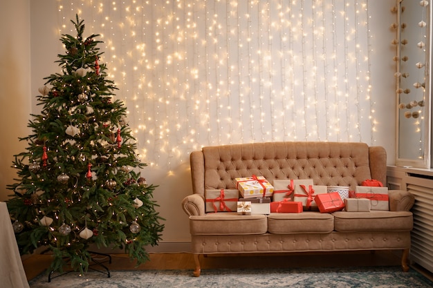Festliches Interieur mit vielen Geschenken auf bequemem Sofa und geschmücktem Weihnachtsbaum