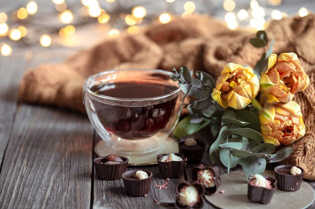 Festliches Stillleben mit einem Getränk in einer Tasse, Pralinen und Blumen