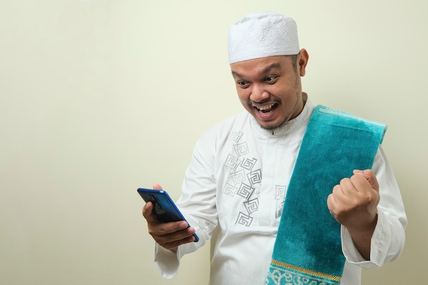 Fette asiatische muslimische männer sehen überrascht von den guten nachrichten, die er von seinem smartphone erhalten hat