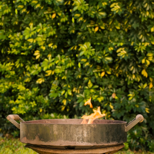 Feuer in der Metallgrillschüssel auf grünem Yard