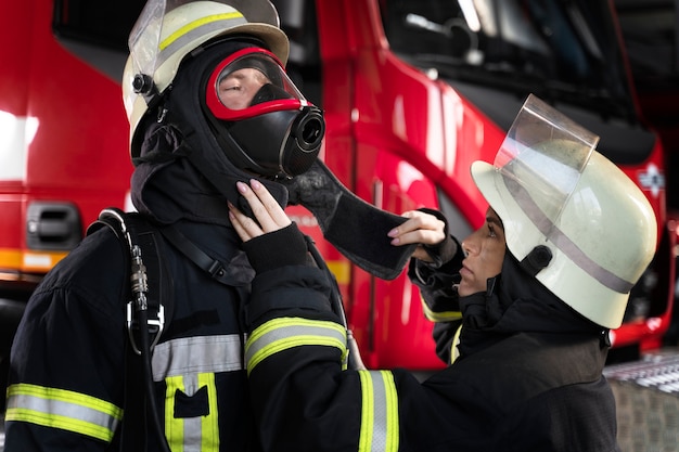 Feuerwehrfrau passt die Feuermaske ihres Kollegen an