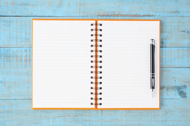 Öffnen Sie orange Notebook und Stift auf blauem Holz Tisch