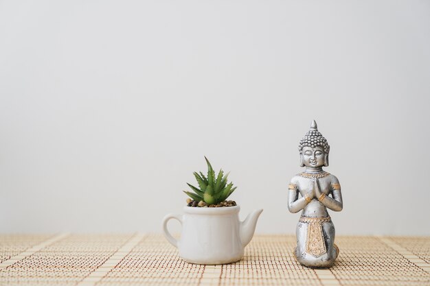 Figur des Buddha neben einem Topf