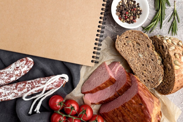 Filetfleisch mit Tomaten und Brot neben Notizbuch