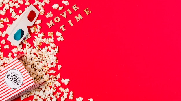 Filmzeittext mit Gläsern 3d und verschüttetem Popcorn auf rotem Hintergrund