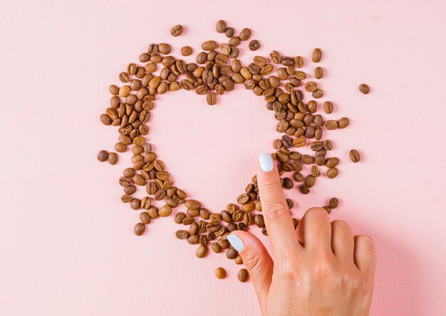 Finger zeigt Herzlücke von Kaffeebohnen