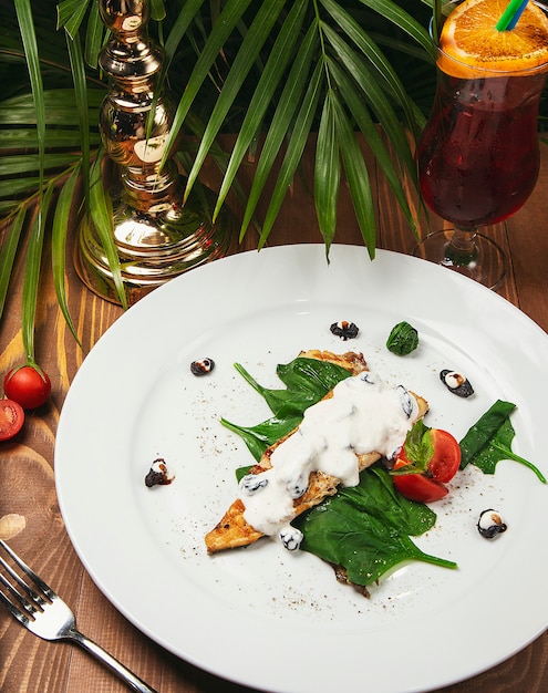 Fischeintopf in einer sahnigen Soße, Tomate, Petersilie auf der Platte, Messer, heller Holztisch der Gabel