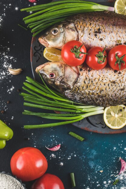 Fischfleisch bereit zum Kochen mit Zitrone, Gemüse und Gewürzen