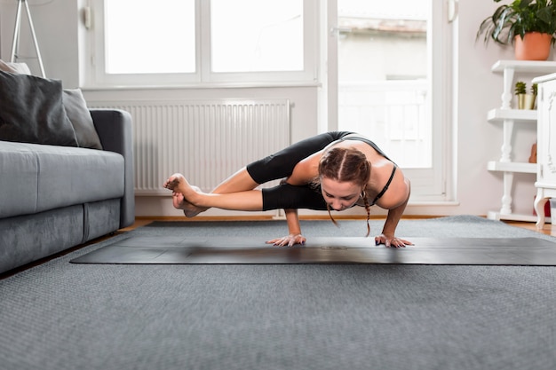 Kostenloses Foto fit frau, die yoga zu hause macht, das in ihren händen steht