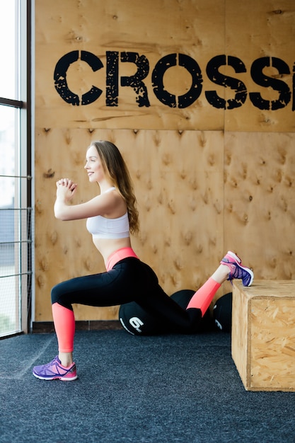 Kostenloses Foto fit junge frau box jumping in einem crossfit-stil fitnessstudio. sportlerin führt boxensprünge im fitnessstudio durch.