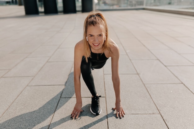 Fit junge frau, die sportuniform trägt, die für das laufen vorbereitet. in voller länge schuss von gesunden jungen kaukasischen frau sprint.